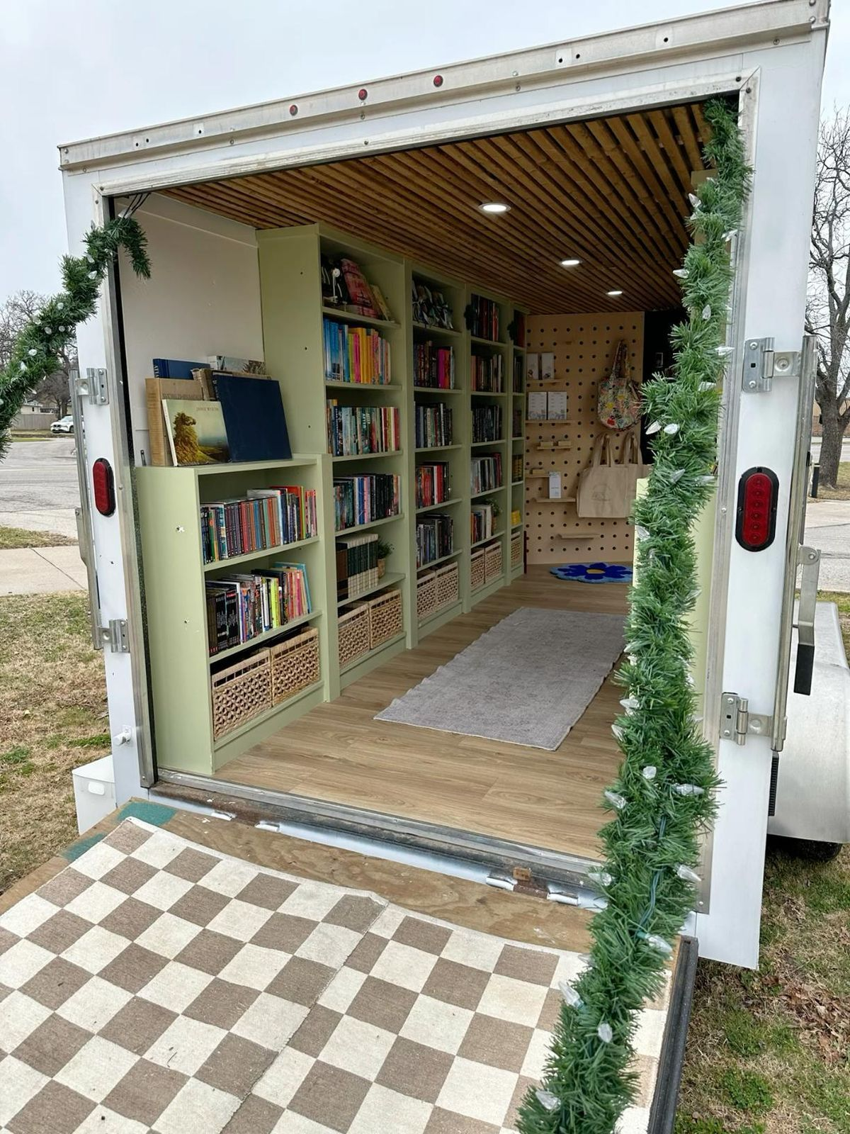 A small mobile book truck with shelves of children's books visiting a neighborhood gathering